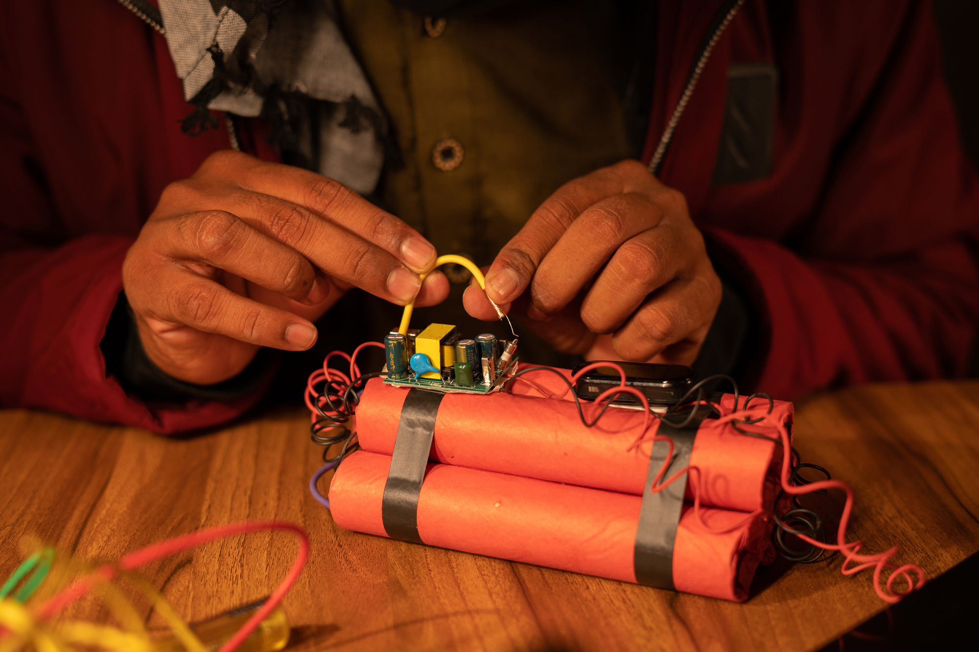 Close up hands of Militant or Naxalite preparing or making timer bomb making with Dynamite - concpet of threat or danger from terrorism